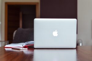 apple macbook na stole z książkami